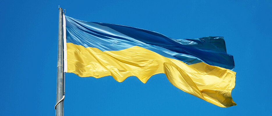 Ukrainische Flagge im Wind vor blauem Himmel.