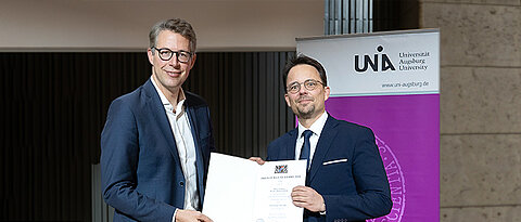 Markus Blume (links) überreicht Prof. Dr. Markus Ludwigs (rechts) die Urkunde.